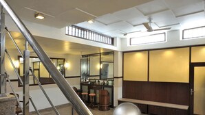A hotel lobby with a staircase, a reception desk, a bench, and a large mirror. - Redbrick villa (Gurugram)