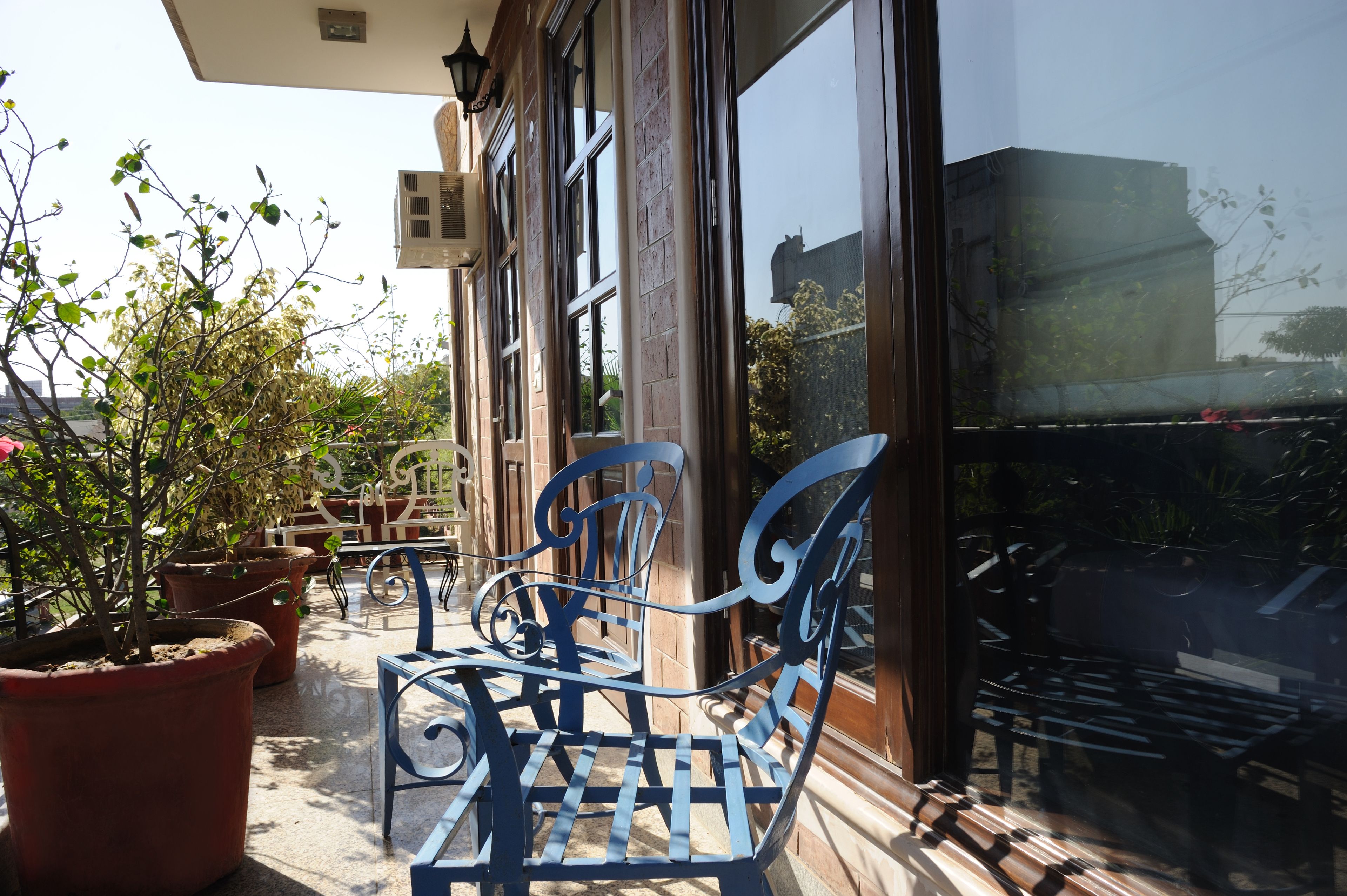 A patio with a metal bench, potted plants, and a building with large windows.