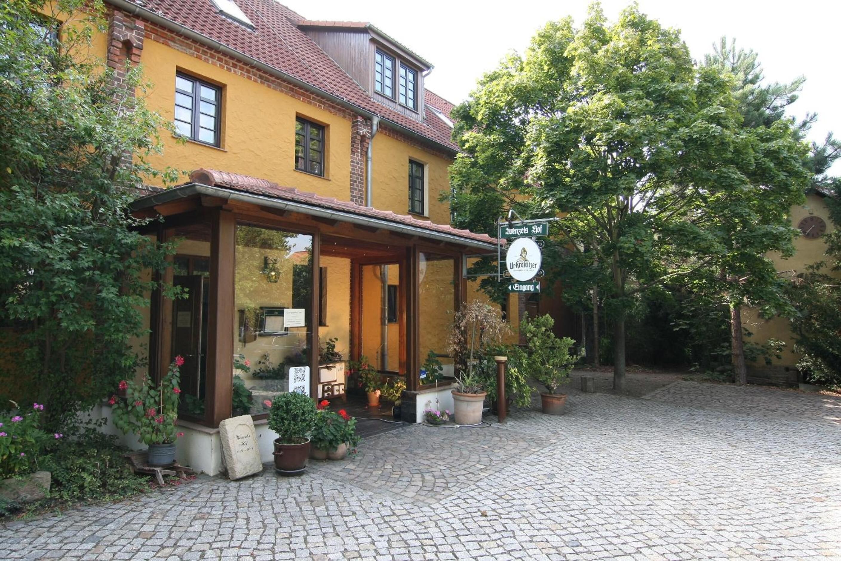 A yellow building with a covered entrance and potted plants.