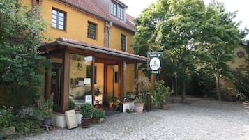 A yellow building with a covered entrance and potted plants.
