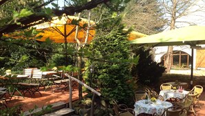 An outdoor patio area with stone steps, wicker furniture, and yellow umbrellas providing shade. - Hotel Wenzels Hof (Beilrode)