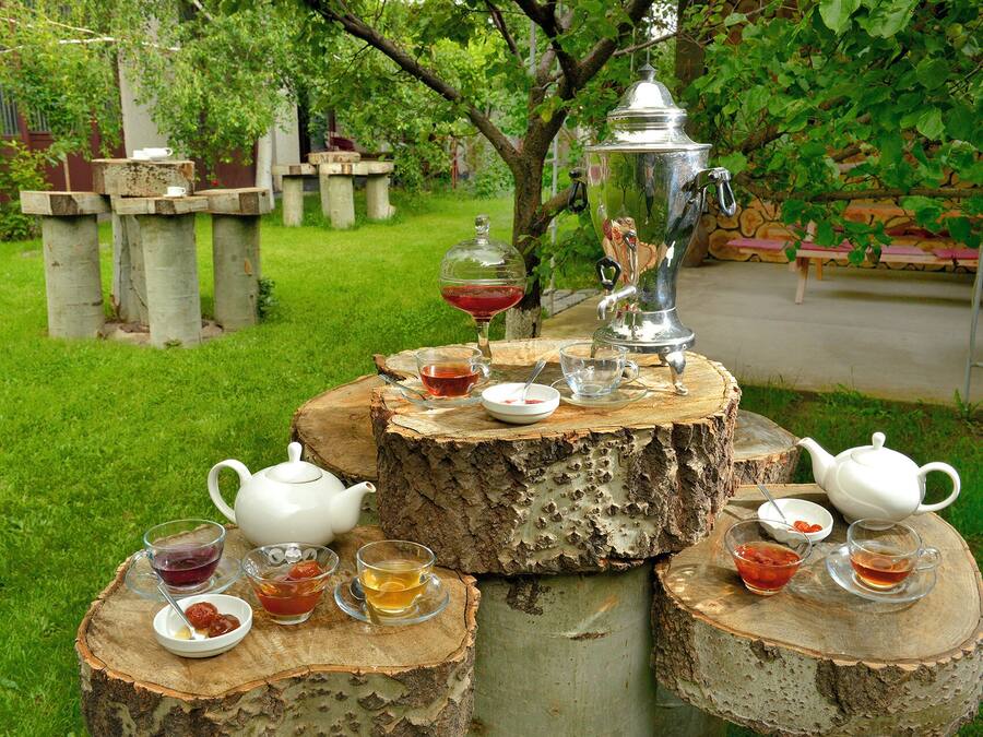 Une table dressée avec des tasses à thé, une théière et un samovar, le tout posé sur un tronc d’arbre.