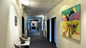 A hallway with a long corridor, framed artwork on the walls, and a large abstract painting. - Berlin Art Hotel (Gyumri)