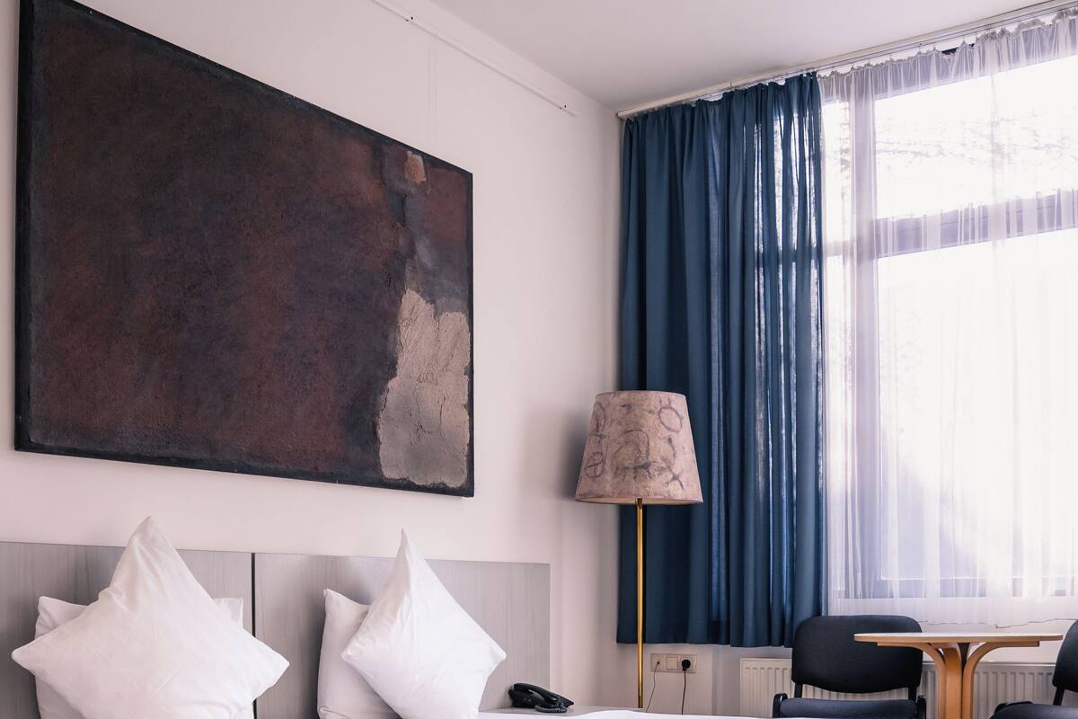 Une chambre d’hôtel avec un grand lit, un bureau, une chaise, une lampe et un tableau au mur.