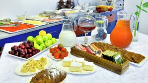 A buffet table with various food items including fruits, pastries, and beverages. - Berlin Art Hotel (Gyumri)