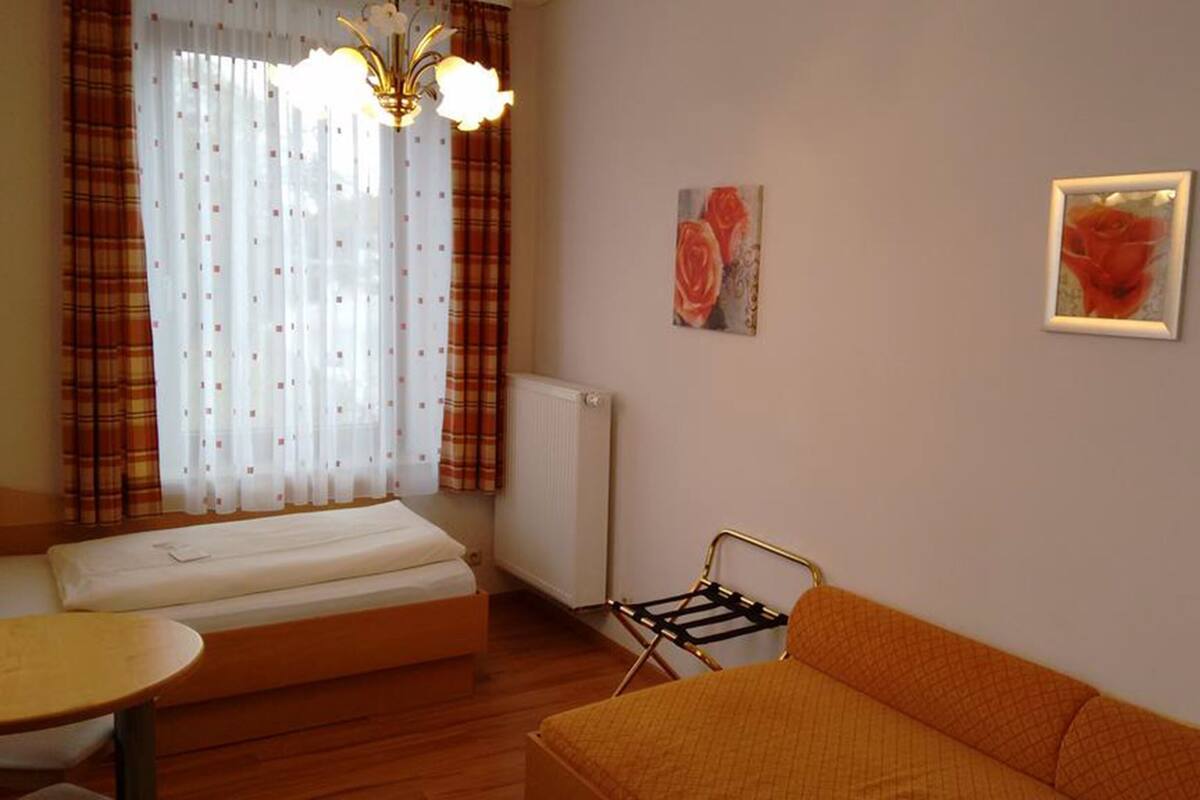 Une chambre à coucher avec un lit, un canapé, une petite table, un radiateur et deux tableaux accrochés au mur.