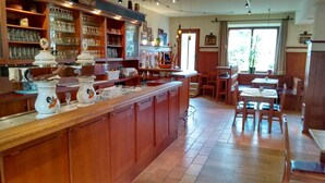 Una cocina amplia con armarios de madera, una isla central y una zona de comedor con sillas y mesas de madera.