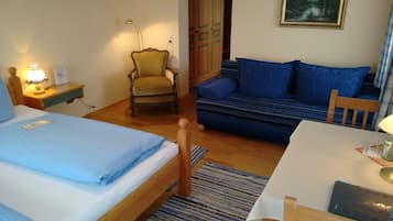 Ein Zimmer mit einem Bett, einem Sessel, einer Couch, einem Schreibtisch und einer Lampe.