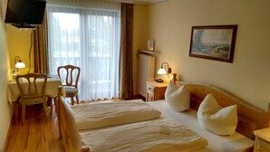 Una habitación de hotel con cama, escritorio, silla y televisión.