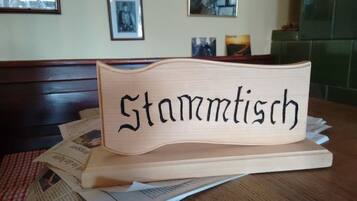 Un letrero de madera con la palabra "Stammtisch" sobre una mesa con periódicos.