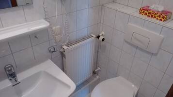 Un baño pequeño con inodoro, lavamanos y un radiador.