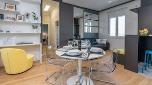 A modern dining area with a round table, clear chairs, and a yellow armchair. - Apartment Veduta (Zadar)