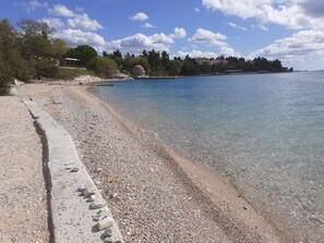 A pebbled beach with a clear view of the sea and a dome structure in the background. - Sunset Beach Apartment (Zadar)