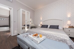 A bedroom with a bed, bedside tables, a wardrobe, and a tray with breakfast items. - Sunset Beach Apartment (Zadar)
