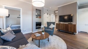 A modern living room with a sofa, armchair, coffee table, and TV. - Sunset Beach Apartment (Zadar)