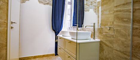 Un baño con pared de piedra, un lavabo blanco y un espejo.