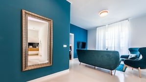 Een moderne woonkamer met blauwgroene wanden, een grote spiegel en een blauwe bank.