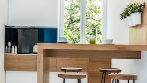 Een moderne keuken met een houten eiland, barkrukken, hanglampen en plantenpotten aan de muur.