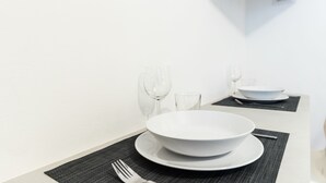 Disposição de mesa limpa e minimalista, com toalha branca, duas tigelas, garfo e copos de vinho.