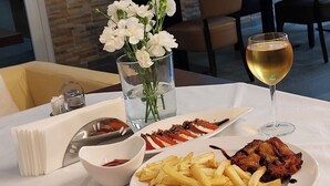Una mesa de comedor con un plato de comida, una copa de vino y un florero con flores.