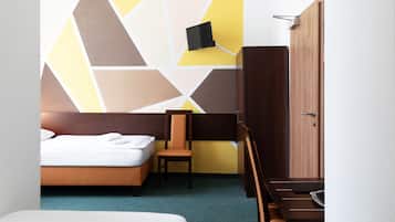 Hotellihuone, jossa on sänky, tuoli, työpöytä ja vaatekaappi.