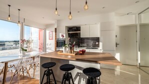 A modern kitchen with a large island, bar stools, and pendant lighting. - Amazing View Apartment (Zadar)