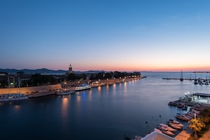 Enjoy a serene waterfront scene with boats docked along the shore and a historic landmark in the distance.