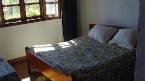 Una camera da letto con un letto in legno, una finestra con tende e una coperta a motivi.