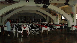 Un'ampia sala con numerosi tavoli e sedie, soffitti a volta e un'area palco.