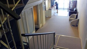 Vestíbulo de hotel con escaleras, una recepción y zona de estar.