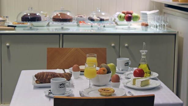 Un bufé de desayuno con diversas bollerías, frutas y bebidas sobre una mesa.
