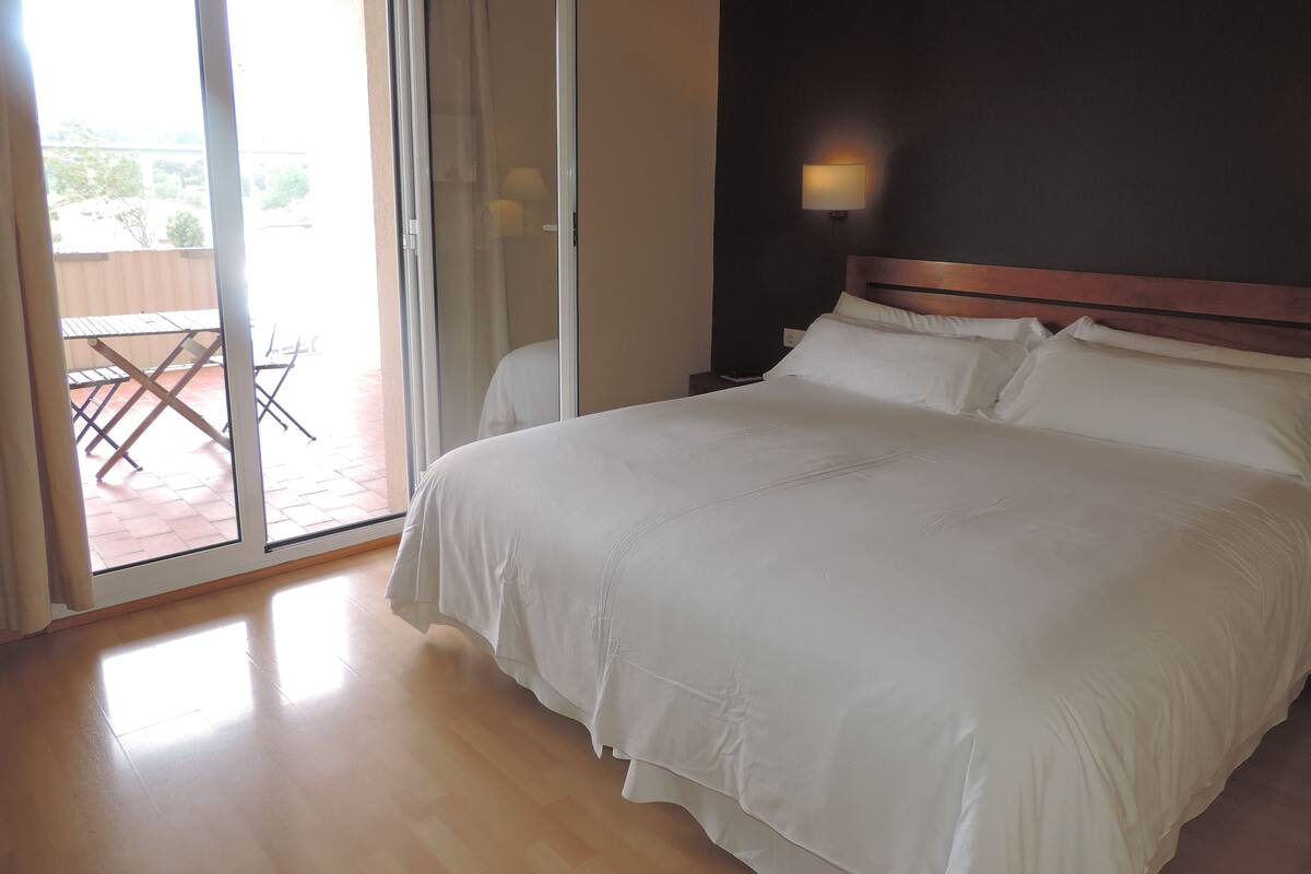 A bedroom with a bed, a nightstand, a lamp, and a sliding glass door leading to an outdoor patio area.
