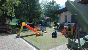 A children's play area with a slide, play structures, and outdoor seating. - Chalet Valeruz (Canazei)