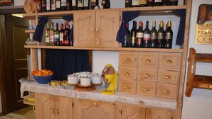 A kitchen counter with wine bottles, a bowl of oranges, and kitchen utensils. - Chalet Valeruz (Canazei)