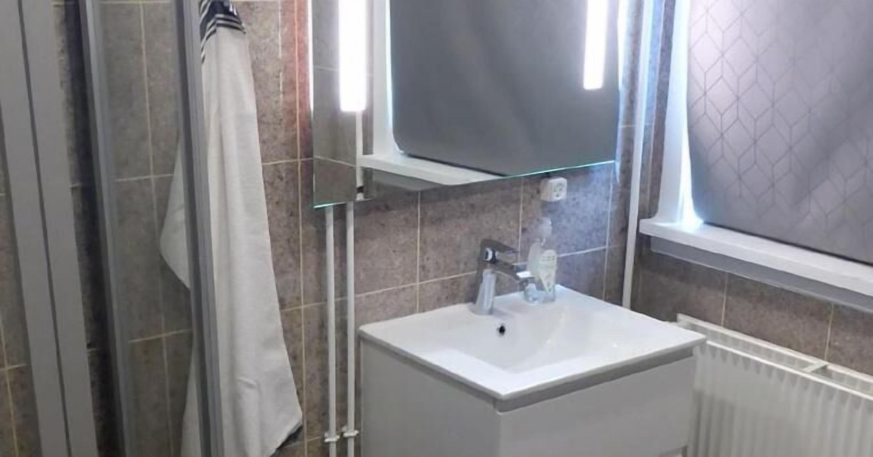 A bathroom with a white sink, a glass shower enclosure, and a window with a view.