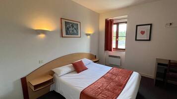 Une chambre d’hôtel avec un lit, des tables de chevet, un bureau et une fenêtre avec des rideaux.