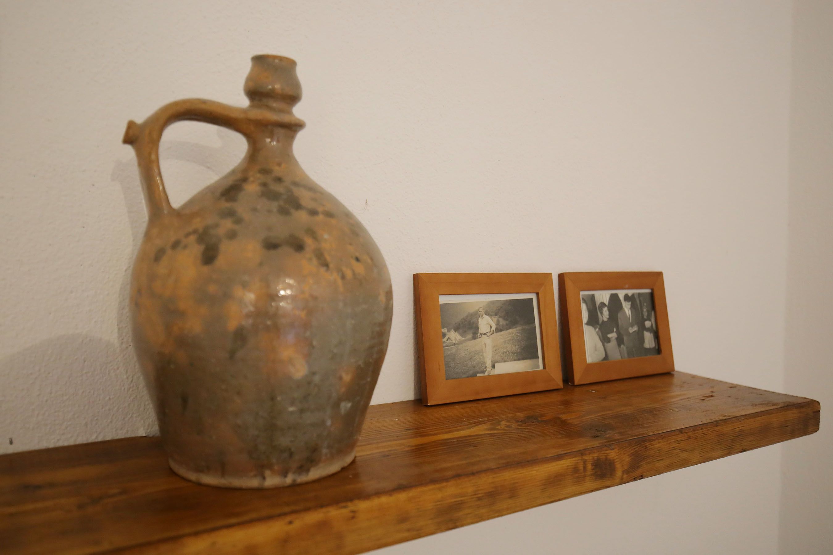 A ceramic jug with a handle on a wooden shelf.