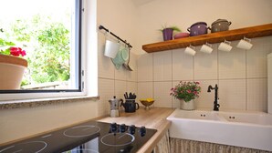 A kitchen with a window, a stove, a sink, and various kitchen items. - Stone House Apartment (Preko)
