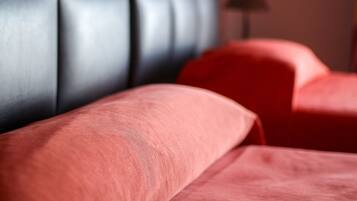 Primer plano de un cabecero tapizado en rojo y un sillón rojo en una habitación.