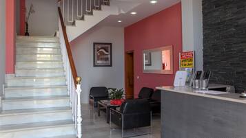 Vestíbulo de hotel con escalera, zona de estar, mostrador de recepción y un cartel que indica venta de entradas.