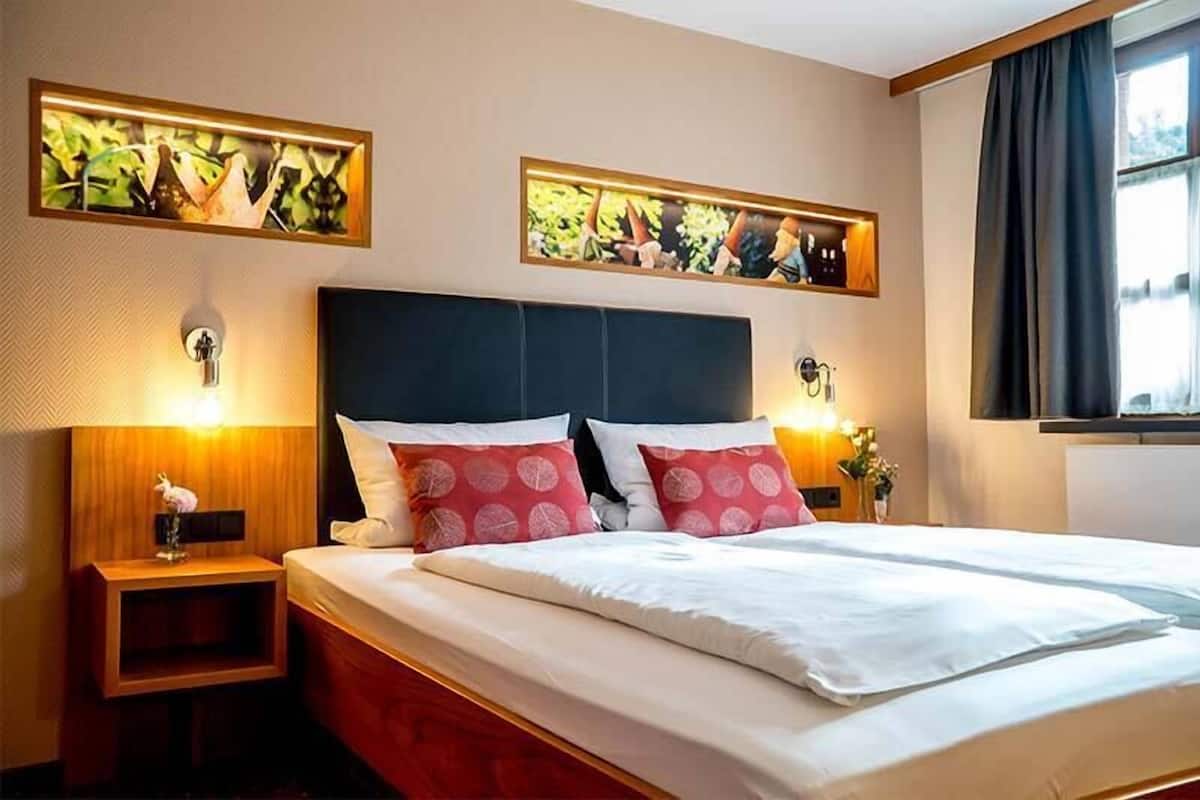 Ein Hotelzimmer mit einem großen Bett, zwei Nachttischen und einem Kunstwerk darüber.