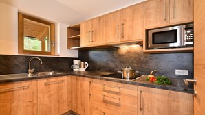 A kitchen with wooden cabinets, a stainless steel microwave, a sink, and a window.