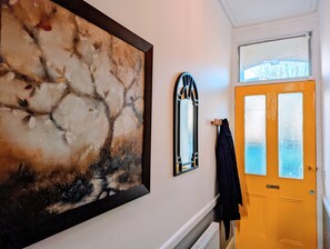 A hallway with a large abstract painting, a mirror, and a door with frosted glass panels. - TopHome Stoke Newington (London)