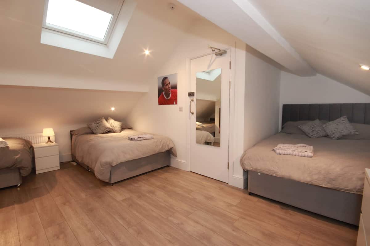 Une chambre avec deux lits, une lucarne, un miroir et une table de chevet avec une lampe.