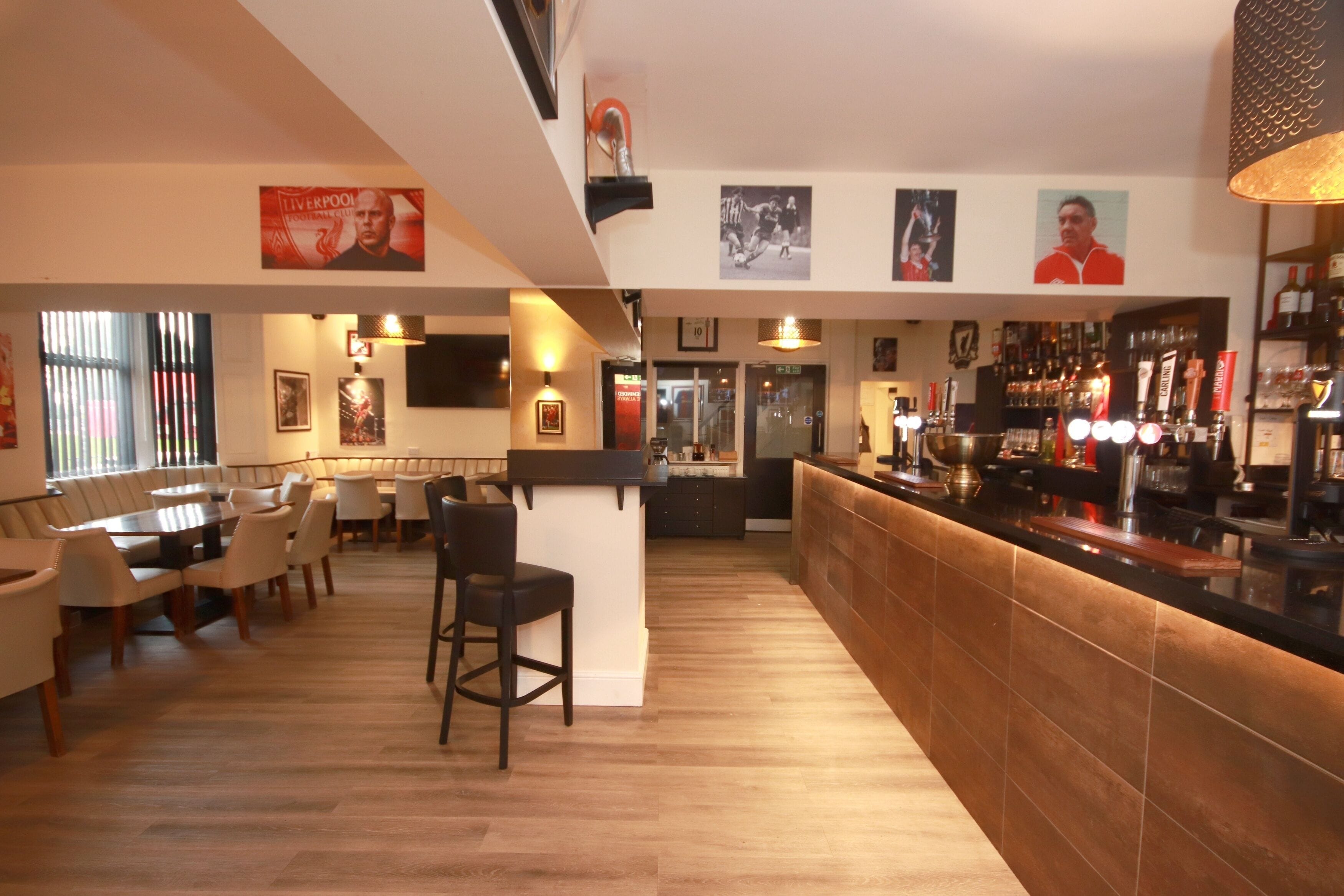 Uma área de bar com um balcão comprido, banquetas e uma variedade de garrafas e copos.