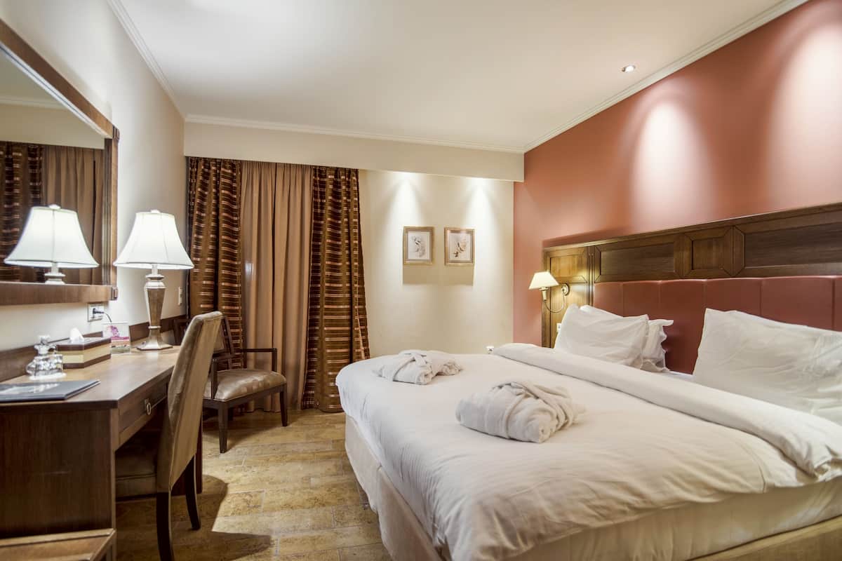 Habitació d'hotel amb llit, escriptori, cadira i mirall.