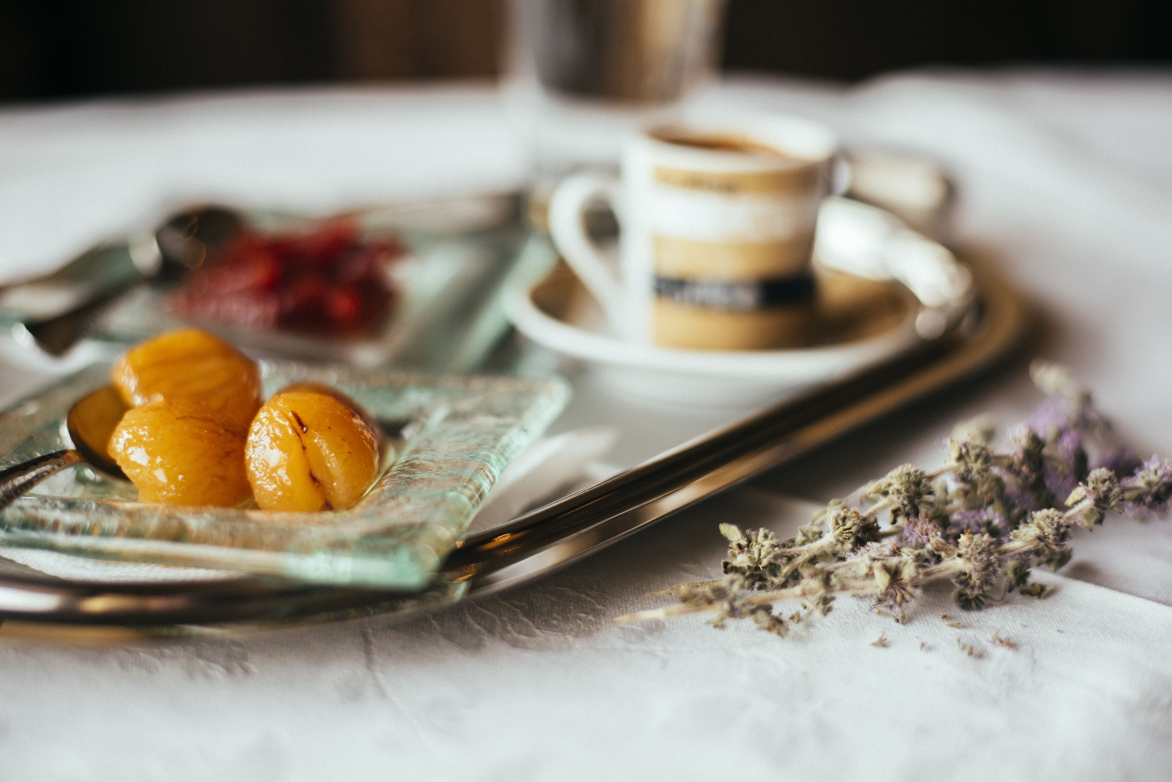 Una bandeja con alimentos, una taza de café y algunas flores sobre una mesa.