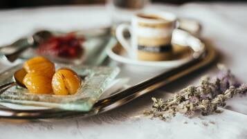 Una bandeja con alimentos, una taza de café y algunas flores sobre una mesa.