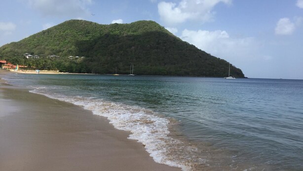 A beach with a small island in the background. - Reduit Orchard 1 Bedroom Apartment (Gros Islet)