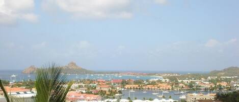 A coastal town with a marina, houses, and a mountain in the background.
